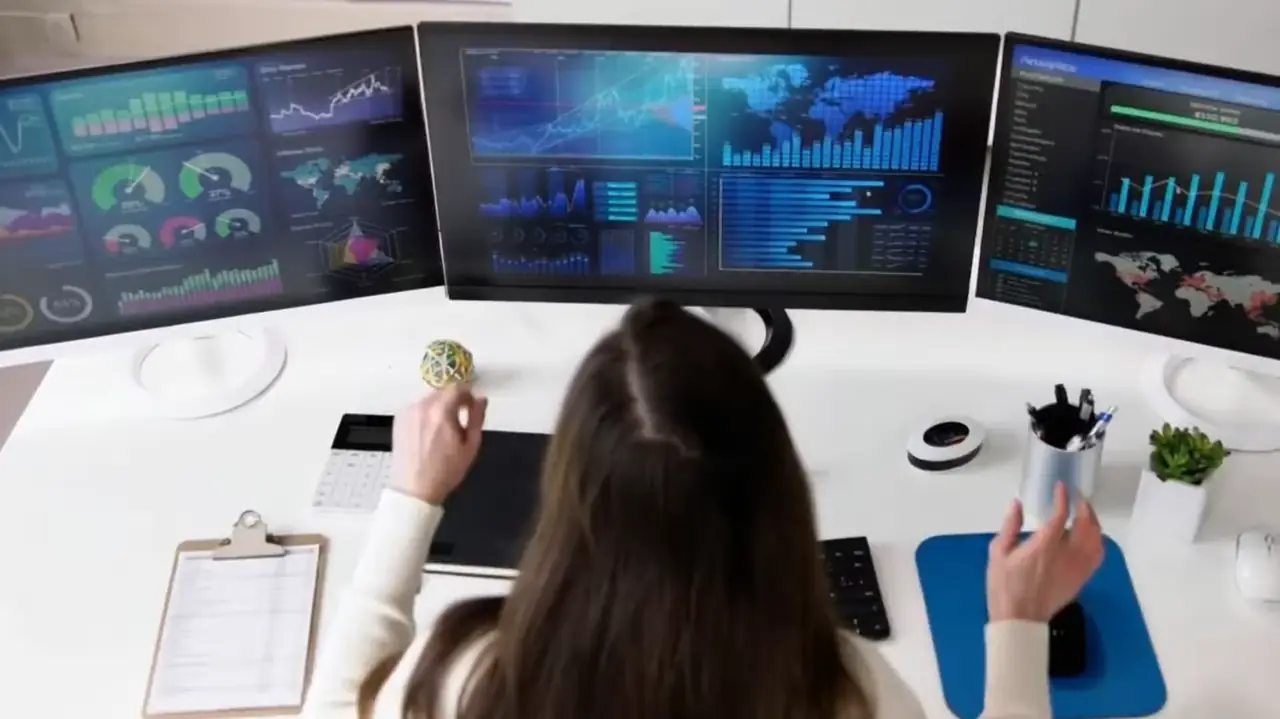 物流データのダッシュボードを表示した3台のモニターで作業するスタッフ
